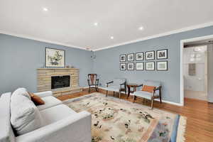 Living room featuring recessed lighting, wood finished floors, a fireplace, and crown molding