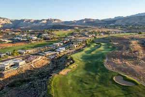 Aerial overview of property's location featuring a mountain backdrop, a golf course, and nearby suburban area