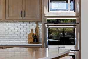 Kitchen view of stainless steel appliances, light countertops, decorative backsplash, and dark brown cabinetry