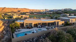 Rear view of property with an in-ground hot tub, a mountain view, a patio area, and stucco siding