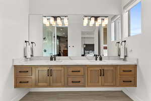 Bathroom featuring ensuite bath, double vanity, a shower, and wood finished floors