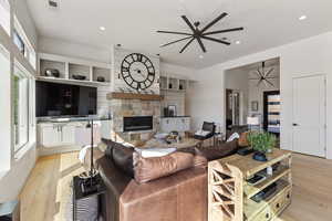 Living room featuring a ceiling fan, light wood-type flooring, a fireplace, and recessed lighting