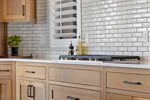 Kitchen with backsplash, light countertops, and stainless steel gas cooktop