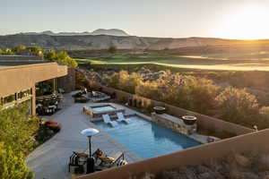 Pool at dusk featuring a mountain view, a patio area, outdoor dining area, an in-ground hot tub, and golf course view