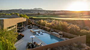 Pool at dusk featuring a mountain view, a patio, outdoor dining area, and golf course view