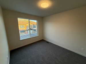 Unfurnished room featuring dark colored carpet and a textured ceiling