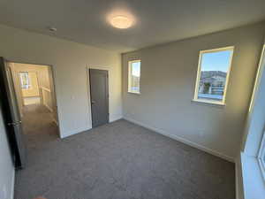 Unfurnished bedroom with dark carpet and freestanding refrigerator