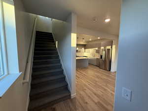 Stairway featuring wood finished floors and recessed lighting