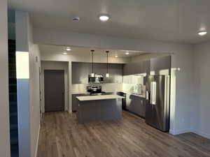 Kitchen featuring stainless steel appliances, dark wood-style flooring, a kitchen island, light countertops, and gray cabinets