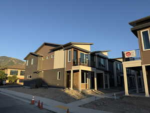 View of front of house featuring a balcony, a mountain view, brick siding, board and batten siding, and a residential view