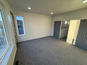 Unfurnished bedroom with dark colored carpet and recessed lighting