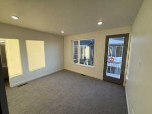 Spare room featuring dark carpet, recessed lighting, and a textured ceiling