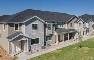 Back of property with board and batten siding, roof with shingles, and a lawn