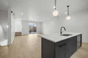 Kitchen featuring dark cabinets, an island with sink, light wood-style floors, modern cabinets, and light countertops