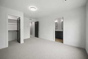 Unfurnished bedroom with a walk in closet, carpet flooring, and connected bathroom