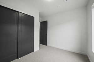 Unfurnished bedroom featuring light colored carpet and a closet