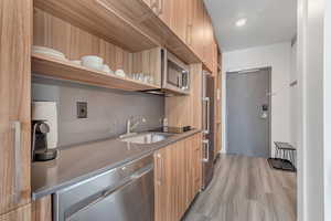 Kitchen featuring open shelves, modern cabinets, stainless steel appliances, and light wood-style flooring