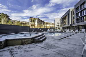 Community pool featuring an in-ground hot tub and a patio area