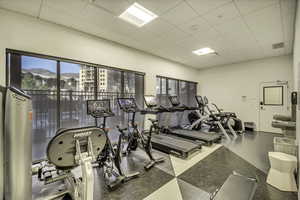 Workout area featuring healthy amount of natural light and a drop ceiling