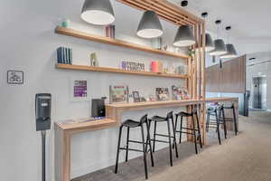 Bar area with elevator, wood finished floors, and hanging light fixtures