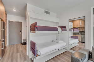 Bedroom with light wood-style flooring and freestanding refrigerator