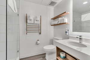 Bathroom featuring wood finished floors, vanity, radiator, and a shower with door