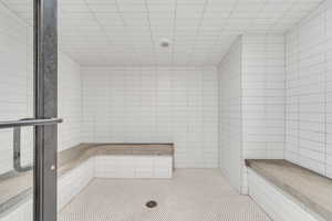 Bathroom featuring a tile shower, tile walls, and tile patterned floors