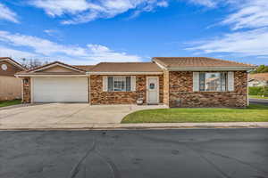 Ranch-style home with concrete driveway, an attached garage, brick siding, and a tile roof