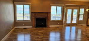 Unfurnished living room featuring a fireplace with flush hearth, wood finished floors, and plenty of natural light