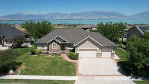 View of front of home with stone siding, an attached garage, driveway, and a water and mountain view