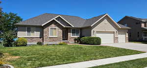 Craftsman house with stucco siding, stone siding, a front lawn, and a garage