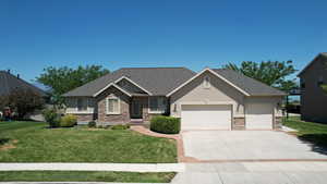 Craftsman-style home with stone siding, a front yard, a garage, and driveway