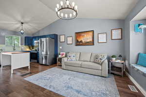 Living room with lofted ceiling, a chandelier, and dark wood-type flooring
