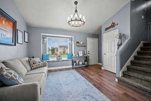Living room featuring a chandelier, wood finished floors, stairway, and lofted ceiling