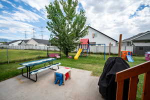 Fenced backyard with a playground, a patio area, and grilling area