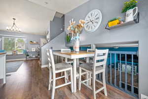 Dining space featuring a chandelier, wood-type flooring, and lofted ceiling