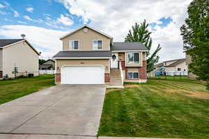 Split level home with brick siding, an attached garage, and concrete driveway