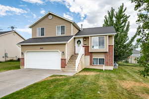 Tri-level home with an attached garage, concrete driveway, brick siding, and roof with shingles