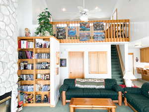 Carpeted living area with a ceiling fan, a stone fireplace, stairway, and recessed lighting