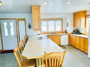 Kitchen featuring white dishwasher, light tile patterned floors, light countertops, recessed lighting, and black electric cooktop