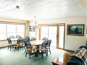 Dining area with a chandelier, light carpet, and a textured ceiling