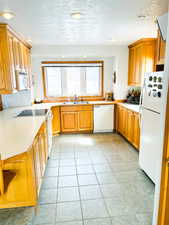 Kitchen with plenty of natural light, white appliances, light tile patterned floors, light countertops, and recessed lighting