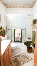Bathroom with vanity, tile patterned flooring, and shower / bath combination with glass door