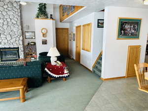 Tiled living area featuring stairway, a stone fireplace, and carpet