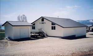 Back of property with a metal roof, a storage unit, and a standing seam roof
