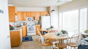 Kitchen featuring white appliances, light countertops, ceiling fan, and light tile patterned floors