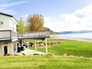 View of grassy yard featuring a deck with water view
