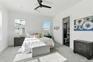 Bedroom featuring light carpet, ensuite bathroom, and ceiling fan