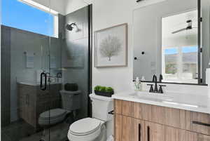 Full bath with a ceiling fan, vanity, and a shower stall