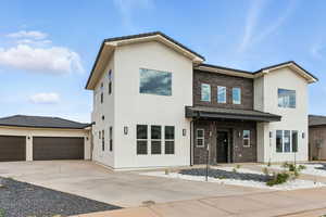 View of front of property with stucco siding, concrete driveway, an attached garage, and a standing seam roof